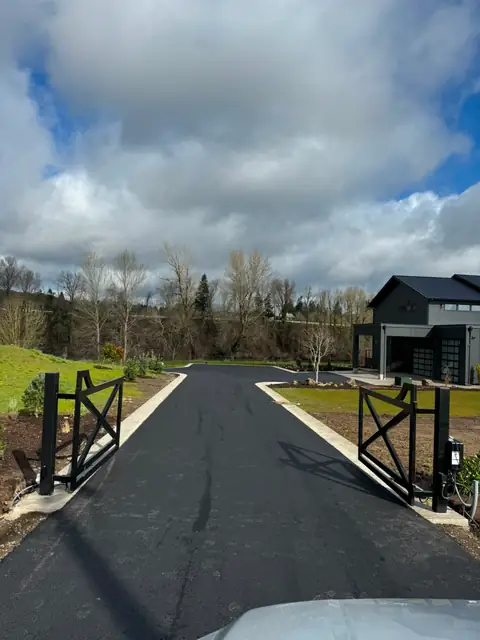 Black metal double swing driveway gate with openers at rural riverside estate