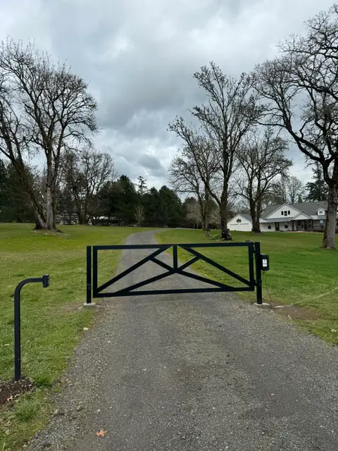 Black steel double swing driveway gate with keypad at rural country property