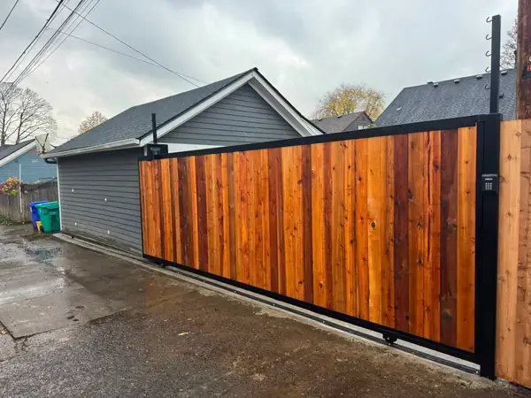 Cedar sliding driveway gate with LiftMaster keypad along paved alley