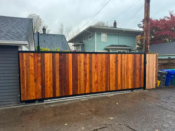 Completed cedar sliding driveway gate with keypad along residential alley