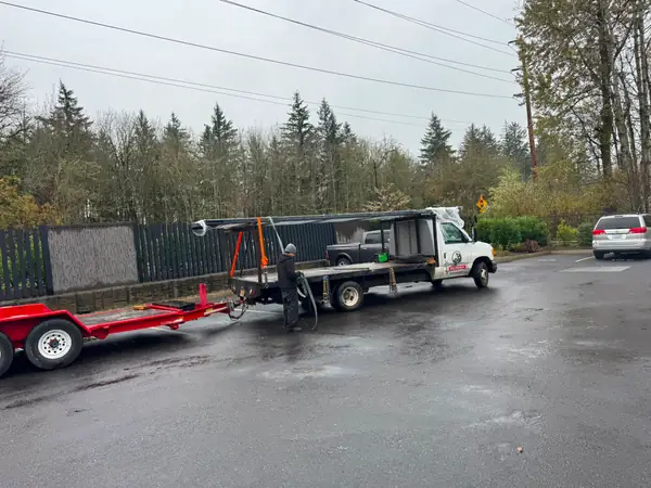 Crew flatbed truck and trailer delivering large gate panels at job site, worker