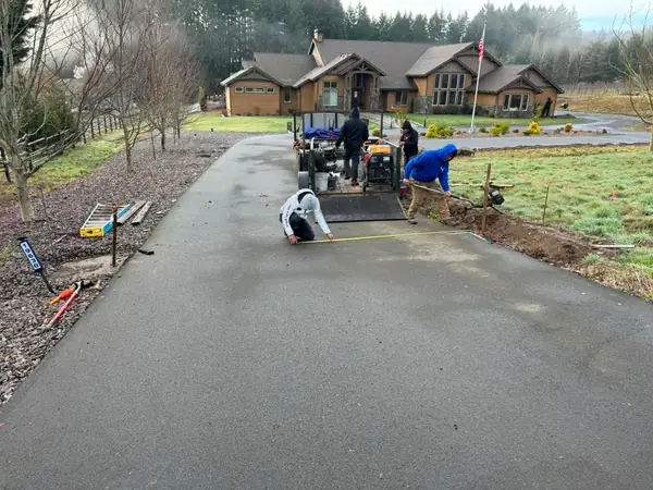 Crew measuring driveway for gate install at rural craftsman home with vineyard