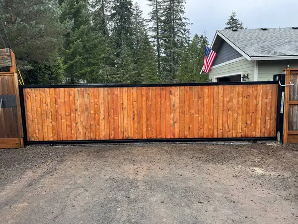 Finished cedar sliding driveway gate with black steel frame at a Pacific Northwest home