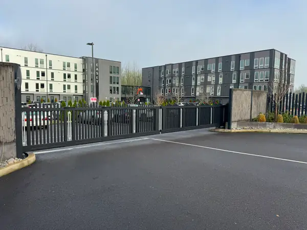 Dark metal sliding security gate at apartment complex parking lot entrance