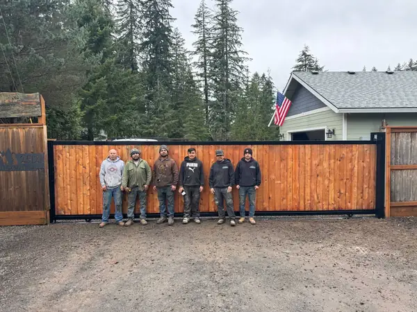 Six-person crew posed in front of a completed cedar sliding gate installation