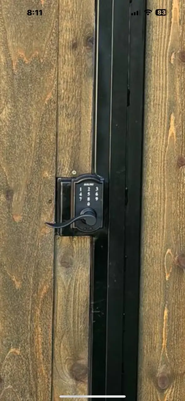 Keypad entry lock installed on a wood pedestrian gate with black steel frame