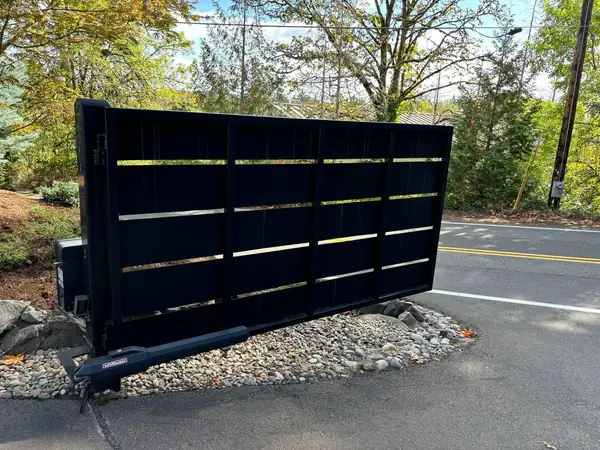 Modern black horizontal-slat steel driveway gate with LiftMaster automatic opener at a Portland residence