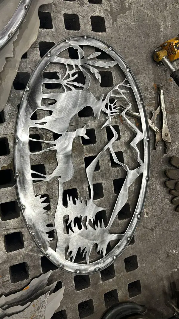 Custom plasma-cut steel gate insert with wildlife forest design on a fabrication table