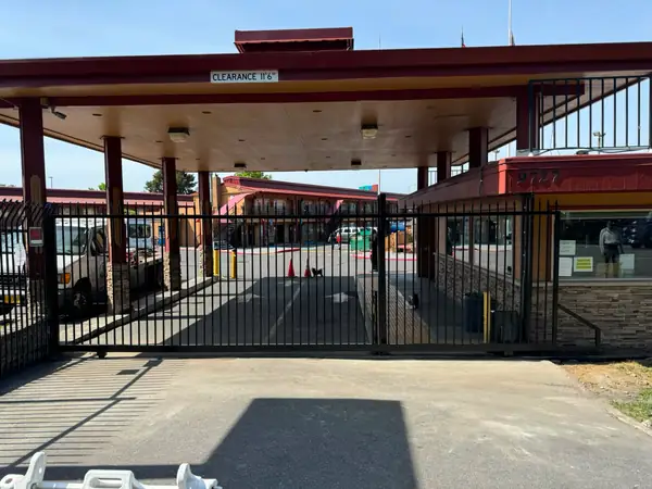 Wide view of motel entrance with black ornamental iron slide gate and canopy